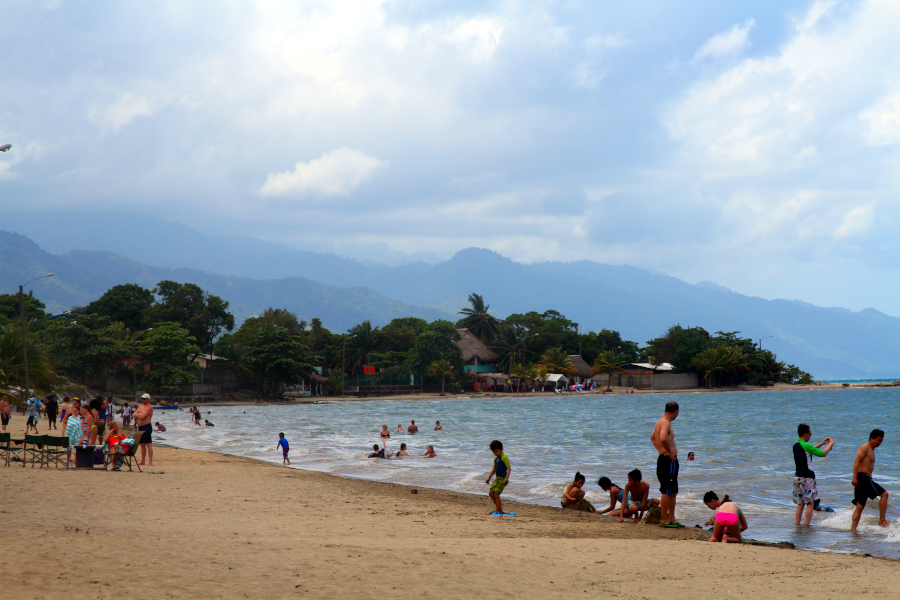 Beach scene with families engaging playfully, illustrating how somatic awareness exercises can be woven into movement, nature, and everyday connection. Trujillo, Honduras Families and children playing on a sandy beach with mountains in the background, a lively setting that reflects connection, presence, and somatic awareness exercises. Trujillo, Honduras.