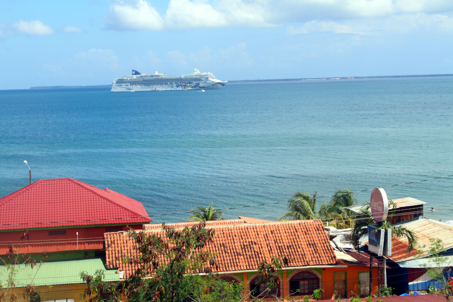 A cruise ship on tranquil seas reflects the steady rhythm of somatic breathing exercises, which bring calm, reduce stress, and restore balance to body and mind. Cruise ship sailing across calm blue water with colorful rooftops in the foreground, symbolizing peace and flow connected to somatic breathing exercises for balance.