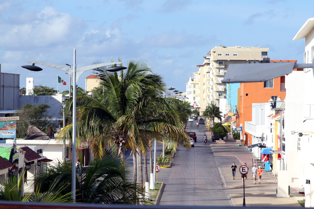 A palm-lined city street reflects balance and flow, themes central to somatic breathing exercises that ease tension, calm the body, and restore everyday presence. Street view lined with palm trees and colorful buildings, symbolizing calm, flow, and awareness connected to somatic breathing exercises for stress relief and grounding.