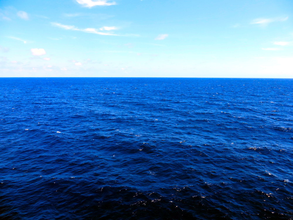 The vast blue ocean reflects somatic therapy benefits—calm, grounding, and emotional release—helping the body and mind find balance like steady waves meeting the horizon. Calm ocean horizon with deep blue waves, symbolizing peace, balance, and somatic therapy benefits.