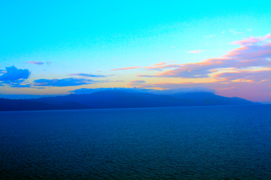 Tranquil seascape with mountains at sunset, symbolizing what is somatic movement as a gentle practice of awareness, balance, and connection to the body. Peaceful ocean view with distant mountains under a colorful sky at dusk, reflecting calm presence and the essence of what is somatic movement through nature and awareness.